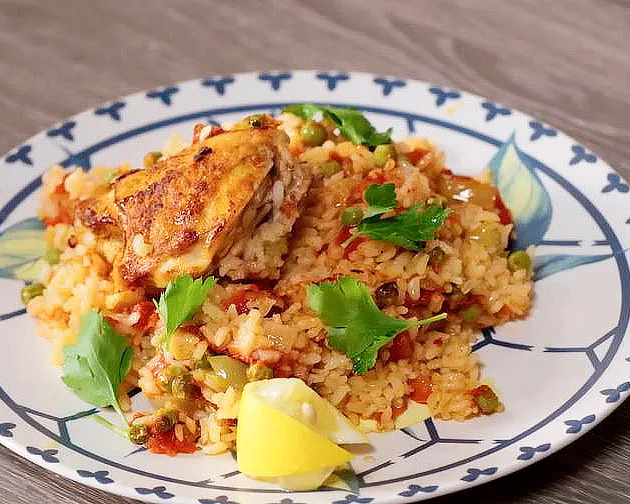 Курица с рисом по-испански - Рецепт курицы с рисом по-испански: куриные бедра кладем на обильно смазанную растительным маслом сковороду. Через несколько минут кладем нарезанный слайсами чеснок. Жарить курицу до готовности не нужно, важна только золотистая корочка. Добавляем соль, перец и паприку. Курица с рисом по-испански - Рецепт